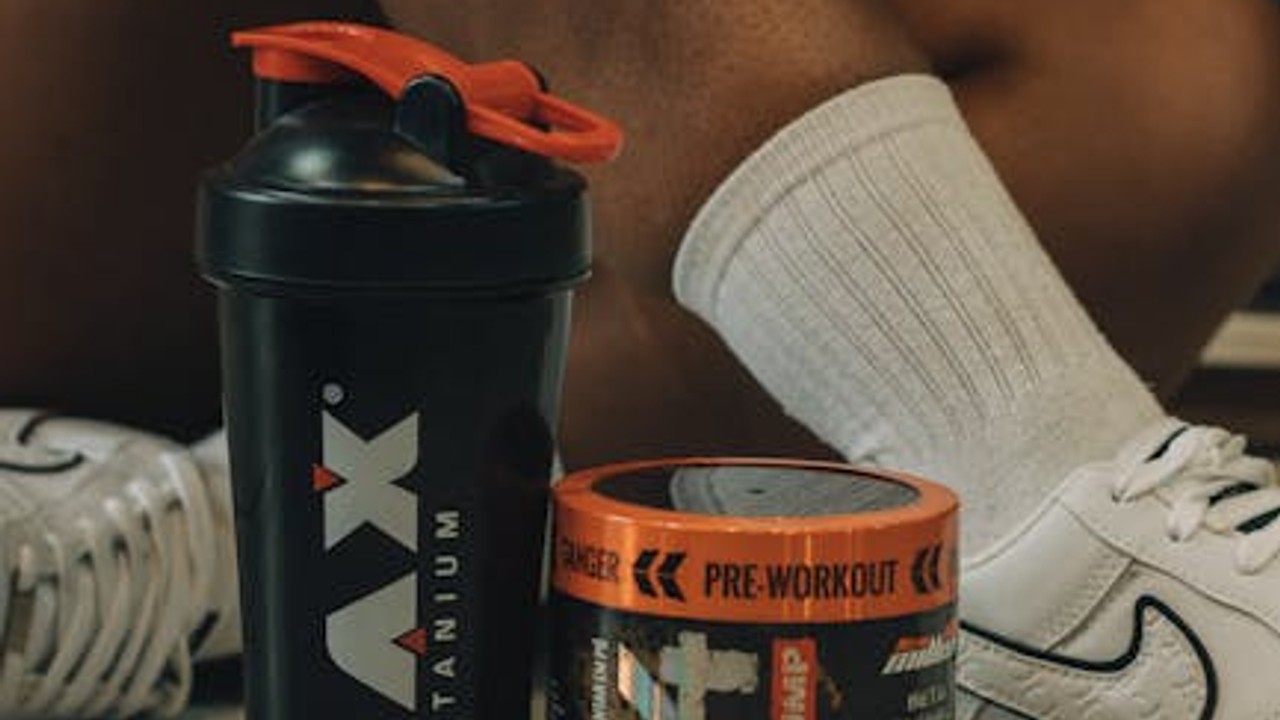 A person in the gym, holding a pre-workout supplement