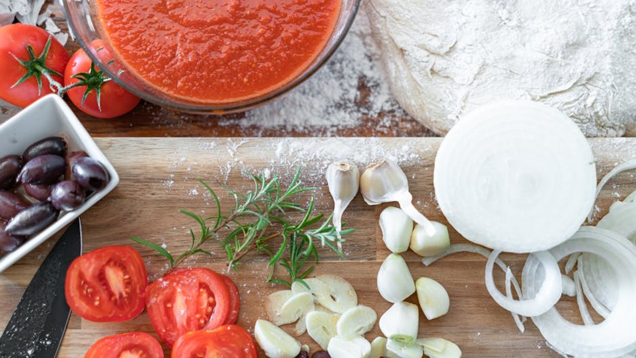 A close-up of fresh Mediterranean ingredients like ripe tomatoes, olives, garlic, and fresh herbs.
